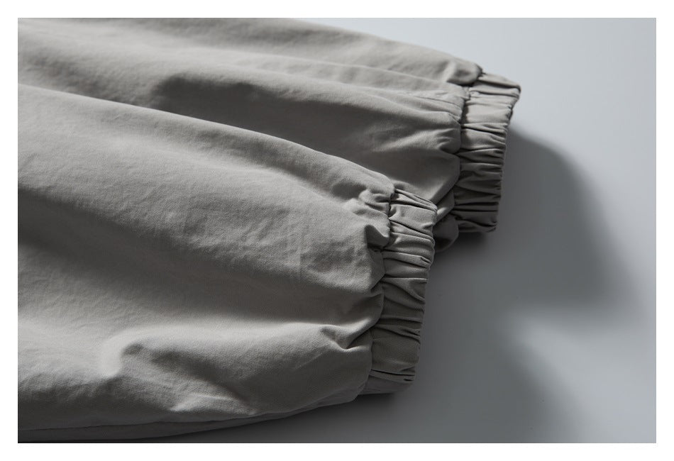 Close-up of two gathered elastic cuffs on a light gray garment.