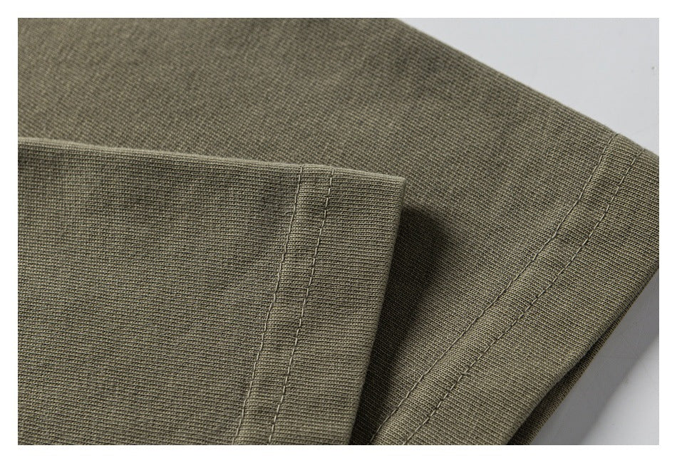 Close-up of olive-gray knit garment fabric with parallel stitched seams.