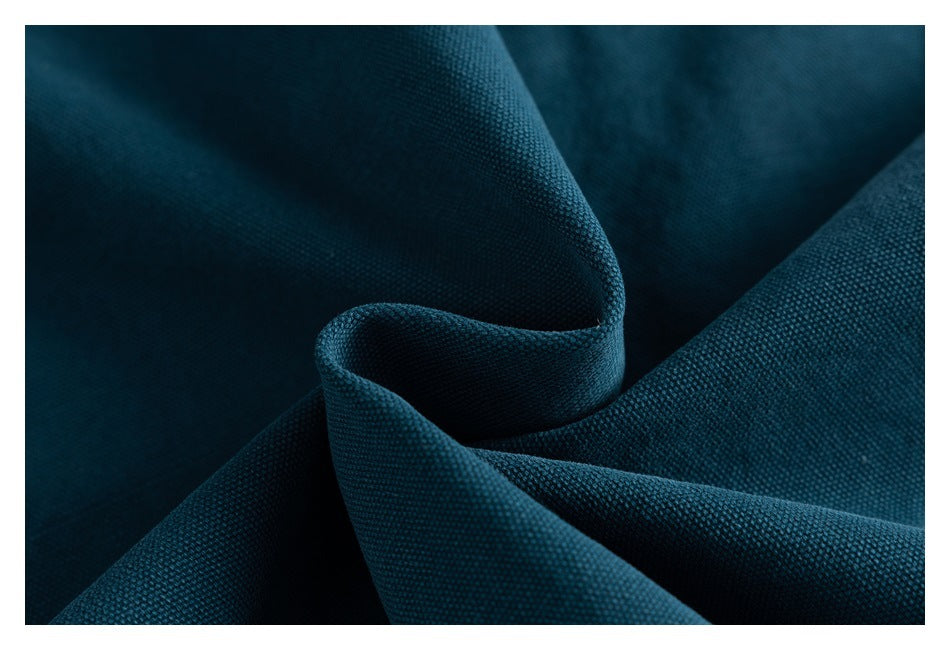 Macro view of deep teal garment fabric arranged in folds, highlighting its textured weave.
