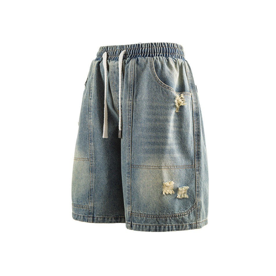 Washed blue denim shorts with elastic drawstring waist, frayed distressed spots and contrast topstitching, angled front view