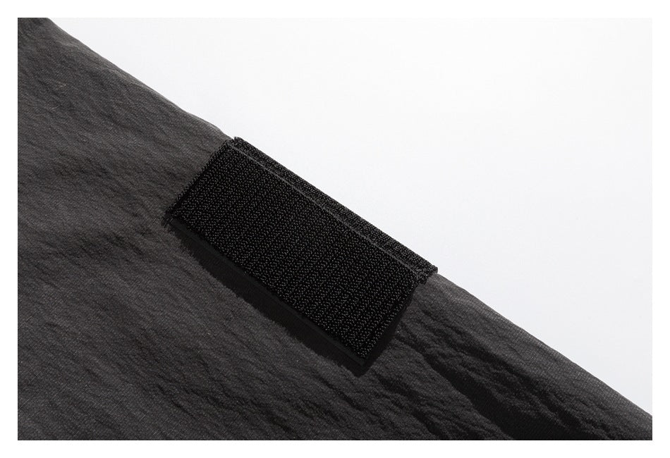 Close-up of a wide black hook-and-loop tab fastened to dark charcoal garment fabric.