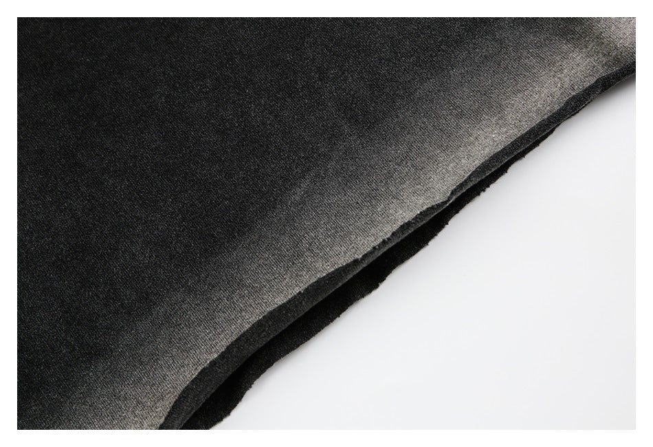 Close-up of the layered edge of a charcoal garment, showing its dark fabric and unfinished-looking edge.