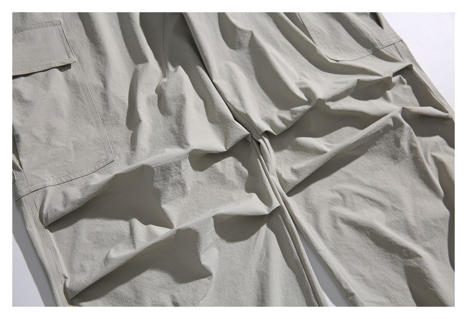 Close-up of light gray cargo joggers showing the leg fabric, stitching, folds, and cargo pocket edge.