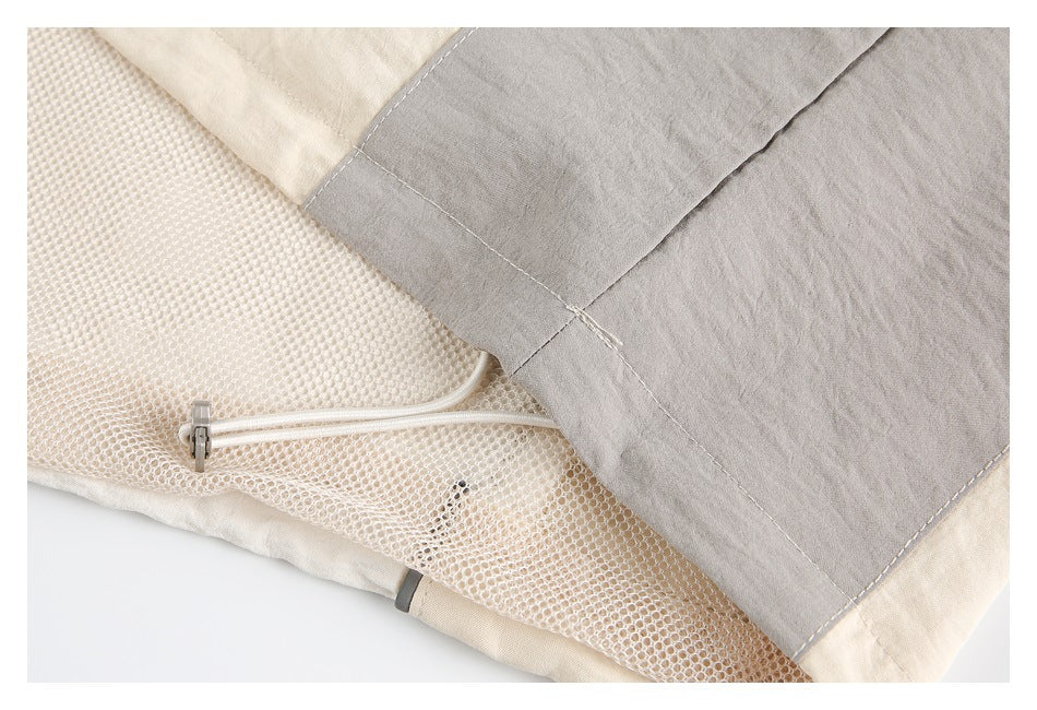 Close-up of a cream and gray jacket interior with mesh lining and a zipper.