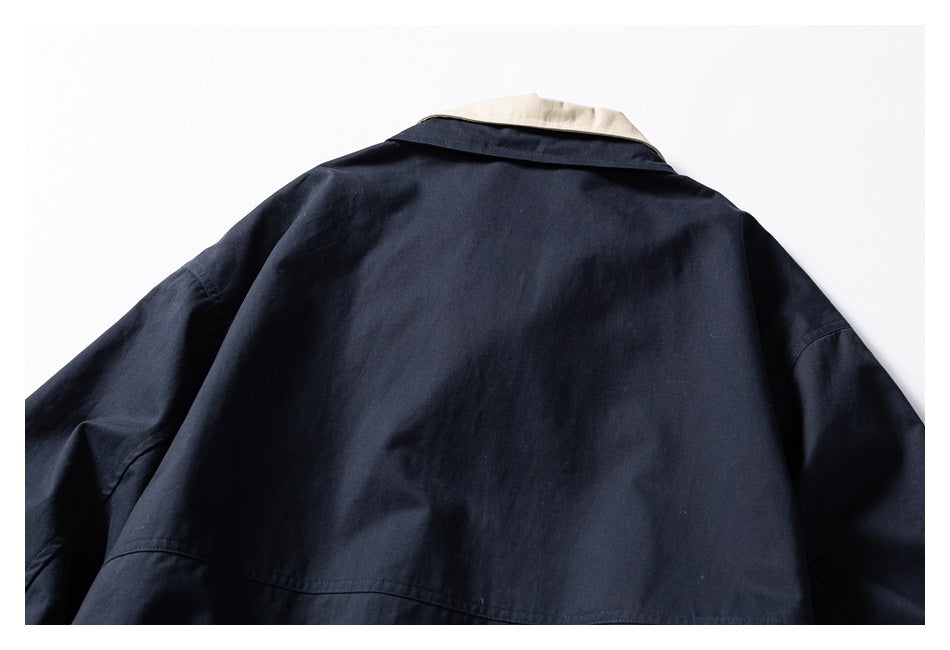 Back view of a dark navy jacket laid flat, with a contrasting cream collar section.