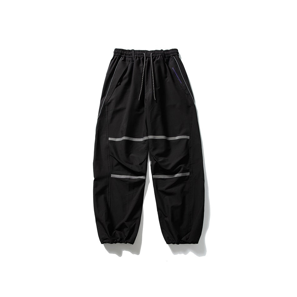 Black loose drawstring pants with gray stripes across the thighs and knees, laid flat