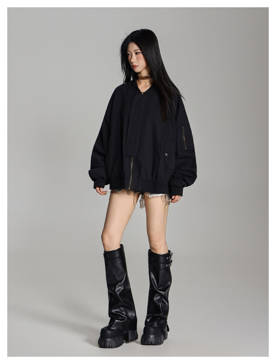 Three-quarter view of a model wearing an oversized black bomber jacket with a covered zipper and zippered sleeve pocket.
