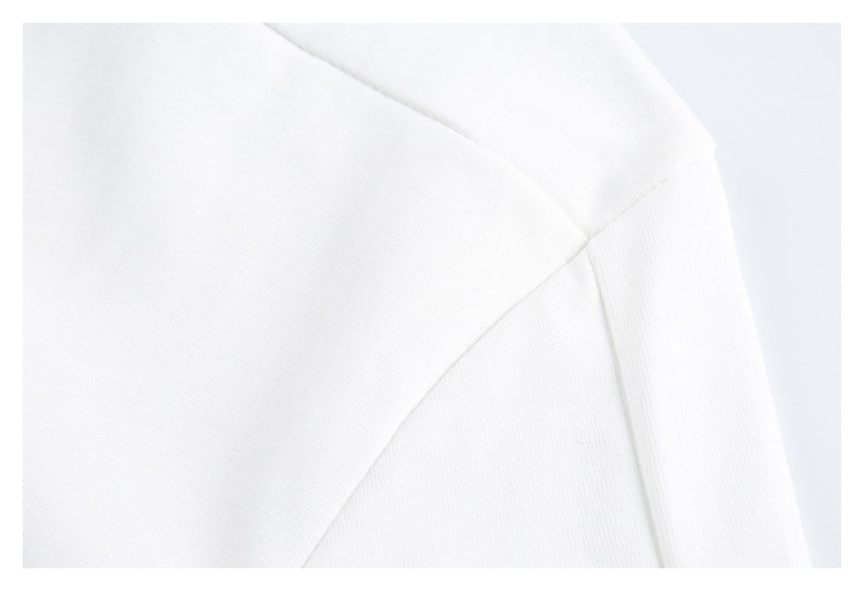 Close-up of a white garment's shoulder seam and ribbed sleeve cuff.