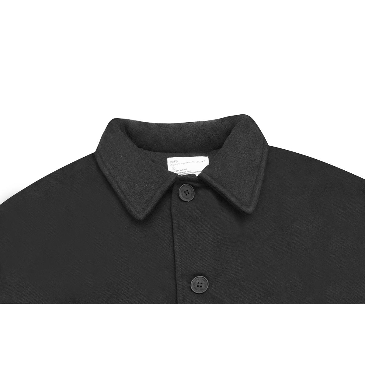 Close-up of a black coat’s wide pointed collar, neck label, and two dark buttons.