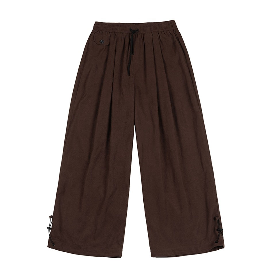 Coffee brown wide-leg drawstring pants with a button-flap pocket and lace-up cord hems, flat lay front view