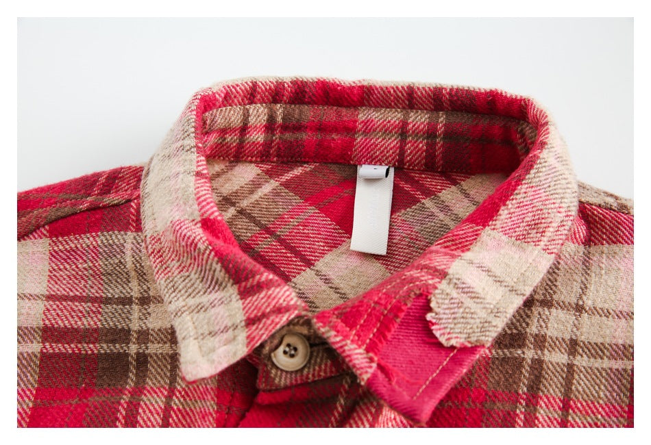 Close-up of the plaid shirt's collar, button and contrasting pink fabric detail.