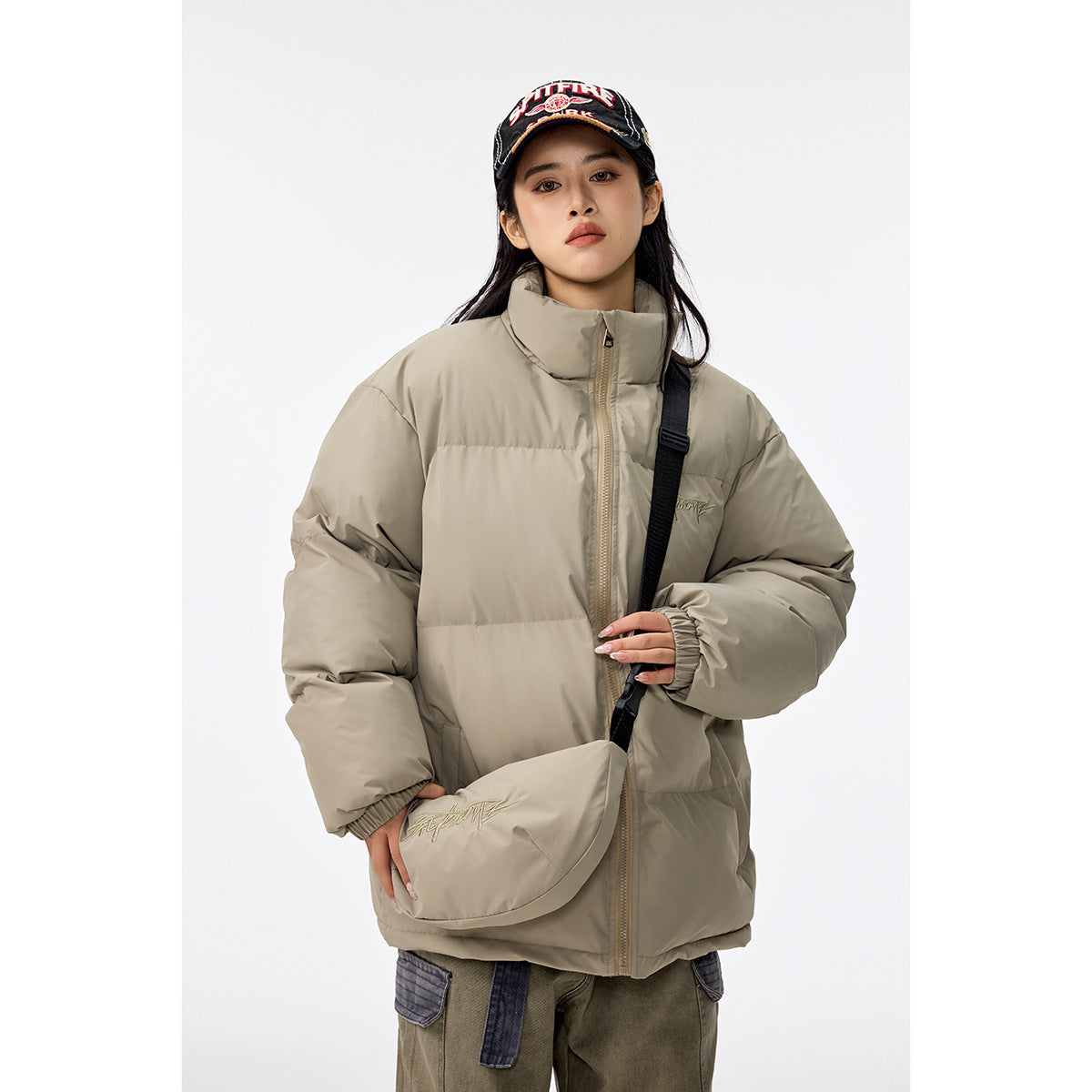 Woman wearing a taupe quilted puffer jacket with a high collar and matching crossbody bag.