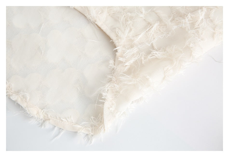 Close-up of ivory mesh fabric with raised floral appliqués and frayed edges.