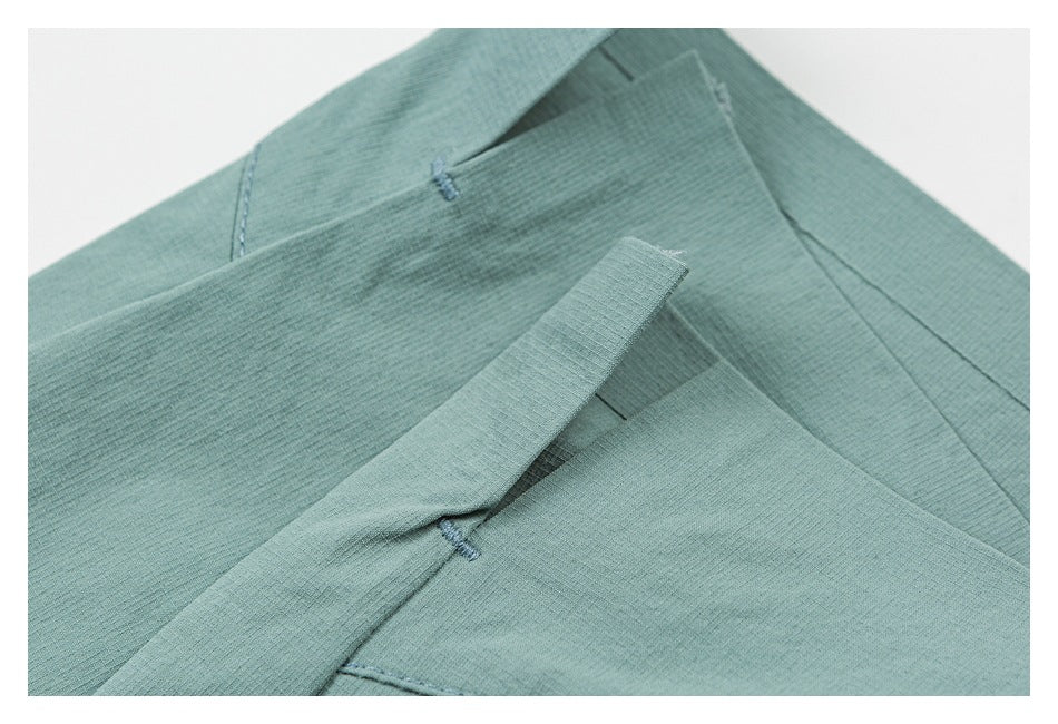 Close-up of a pocket opening and stitching on mint-green shorts.