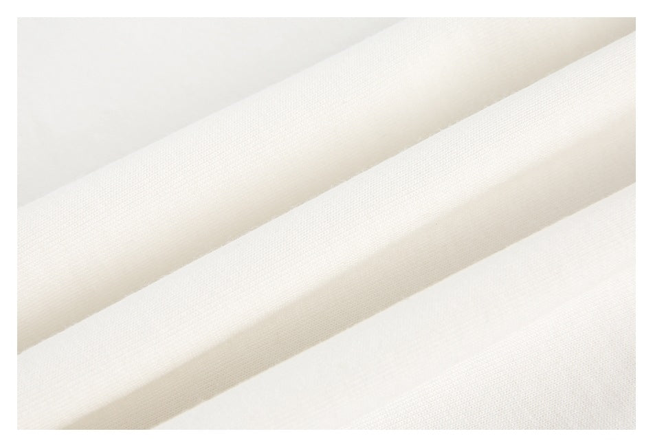 Close-up of white fabric draped in soft folds, showing its fine texture.