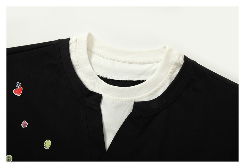 Close-up of the black shirt's split neckline, layered white collar and inset, and small colorful motifs.