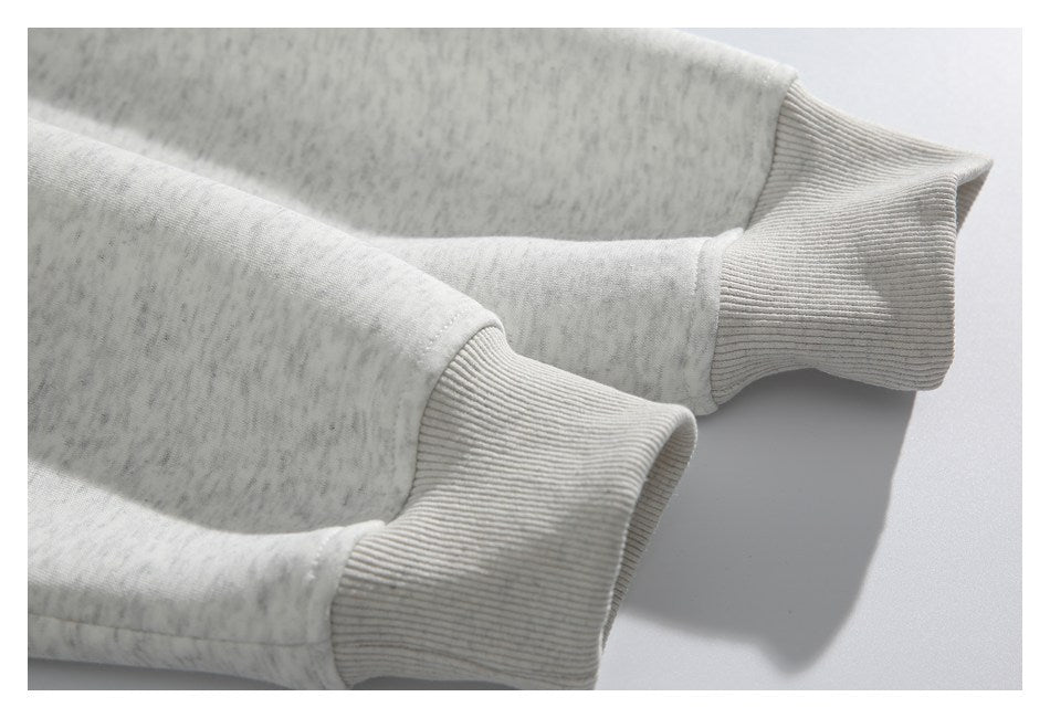 Close-up of the ribbed cuffs and sleeves of a light gray heather sweatshirt.