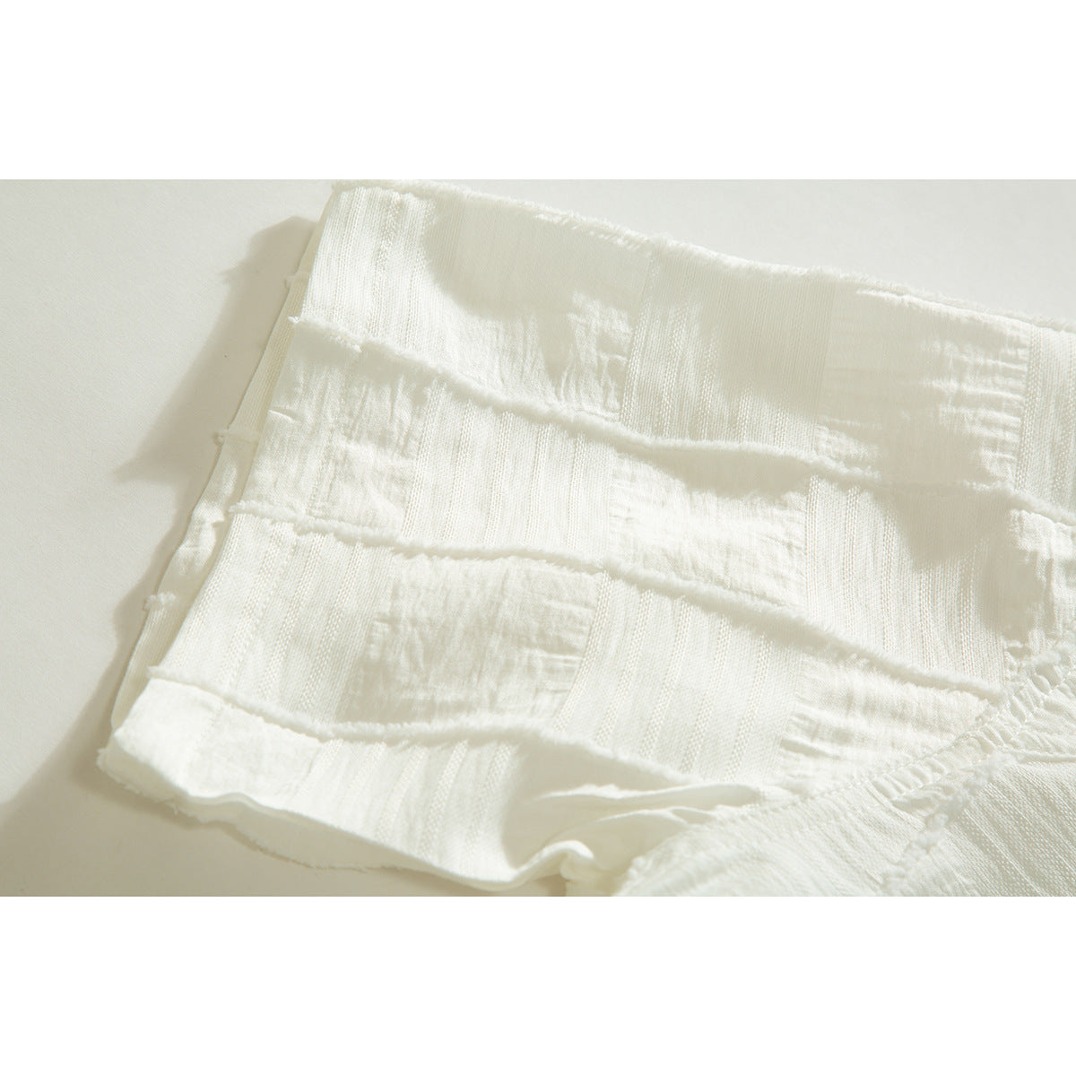 Close-up of an ivory shirt sleeve with textured rectangular panels and a finished cuff.