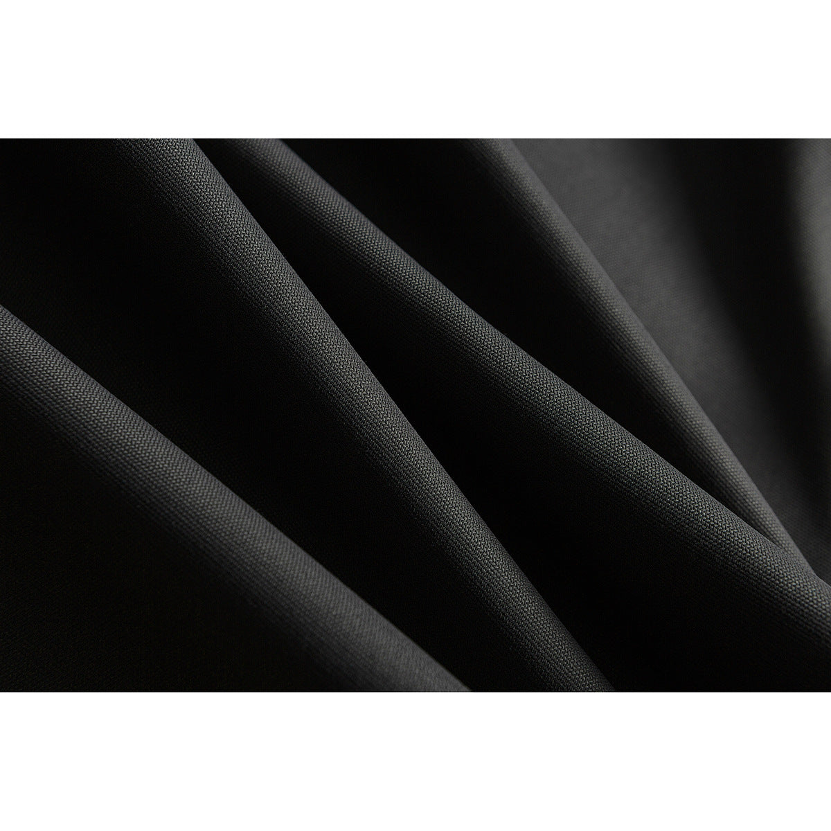Macro view of black fabric draped in folds, showing its textured surface.