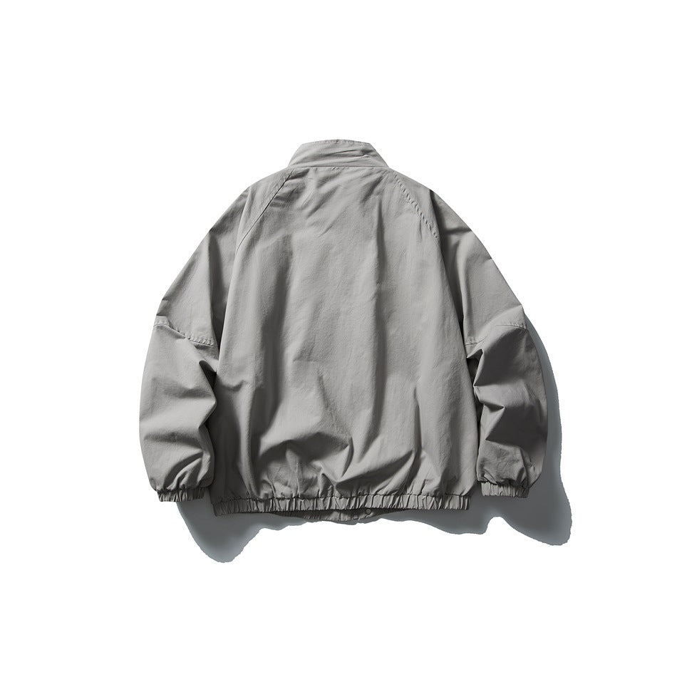Back view of a light gray jacket with a stand collar, roomy sleeves, elastic cuffs, and a gathered hem.