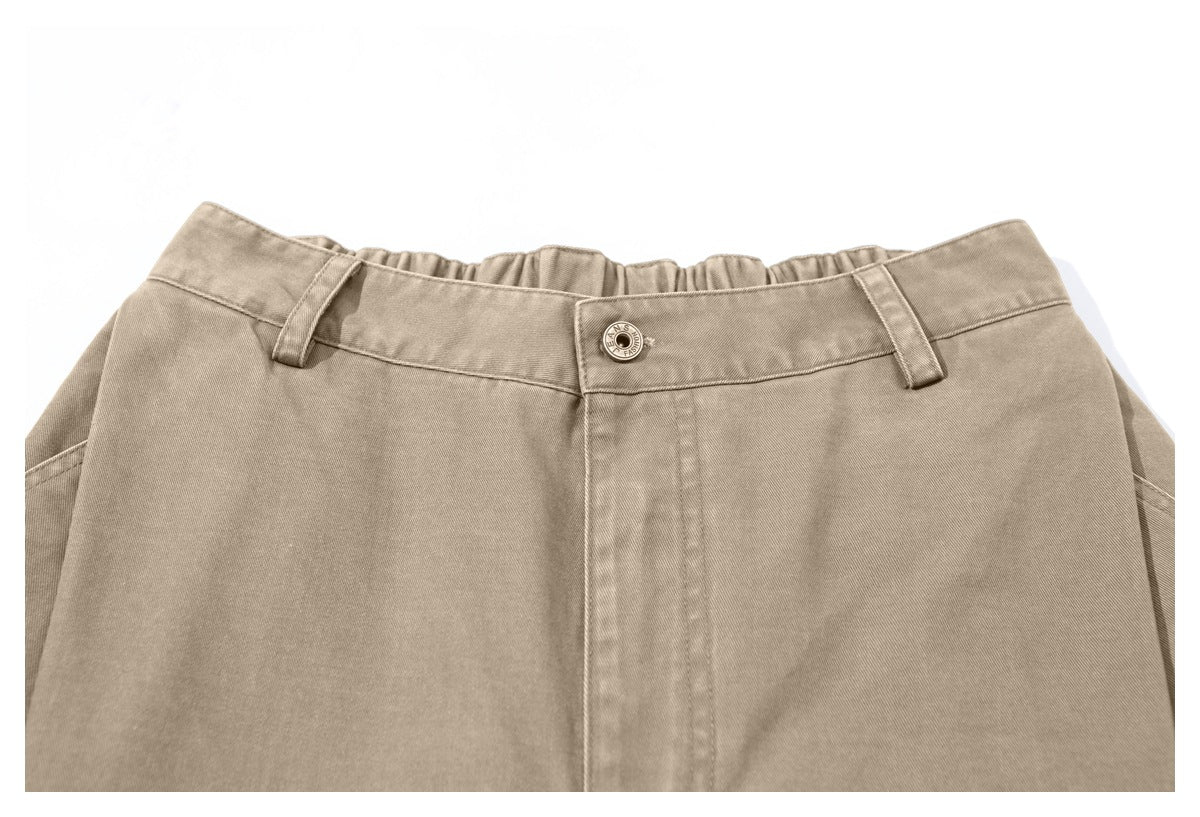 Close-up of taupe trousers showing the buttoned waistband, belt loops, and front fly.