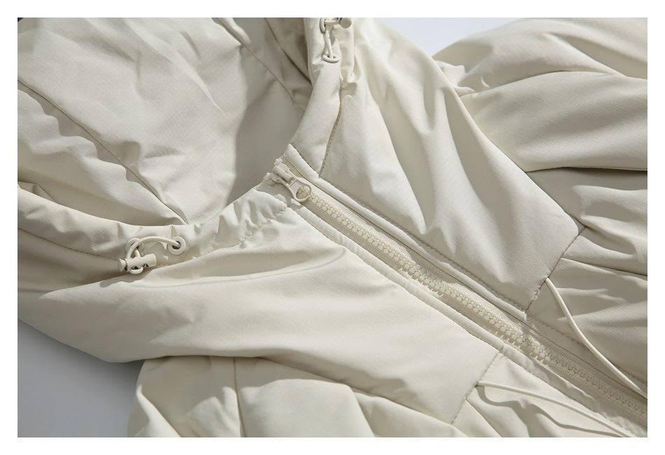 Close-up of an off-white jacket's front zipper, panel seams, and adjustable drawcords.