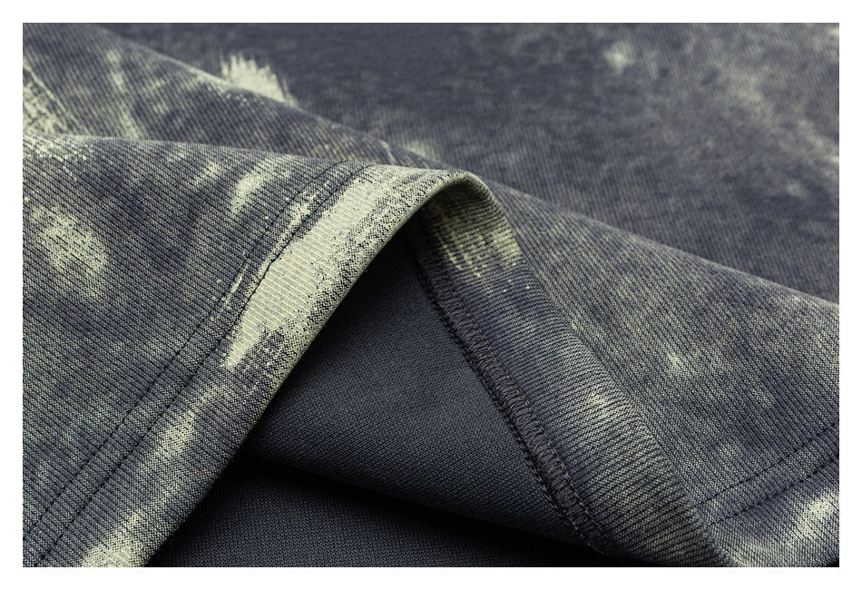 Close-up of a dark garment's folded hem and interior stitching, with a pale abstract print.