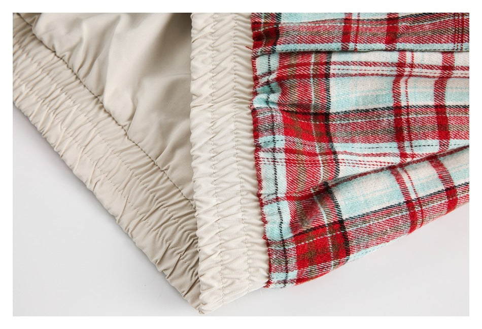 Close-up of gathered cream lining and a seam beside red, cream, and pale blue plaid fabric.