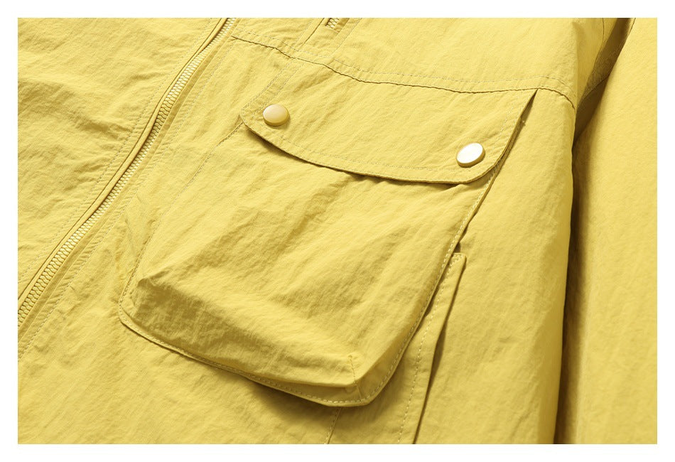Close-up of a large flap pocket with two snap buttons on the yellow jacket.