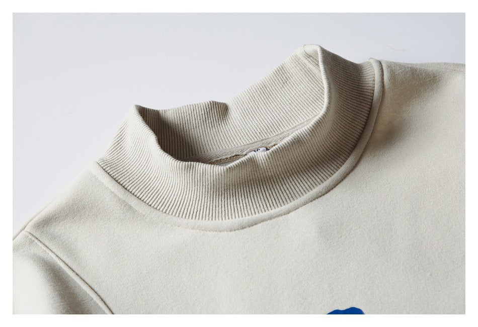 Close-up of an off-white sweatshirt's tall ribbed mock neck and shoulder seam.