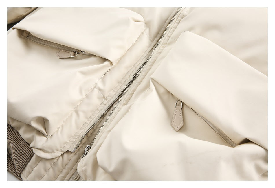 Close-up of the ivory jacket's front zipper and two oversized flap pockets with zipper openings.