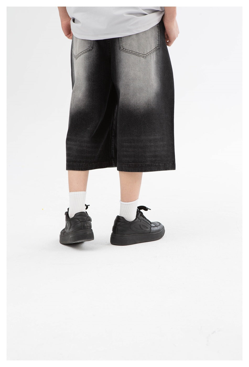Rear close-up of washed black wide-leg shorts showing two back pockets and a faded gray wash.