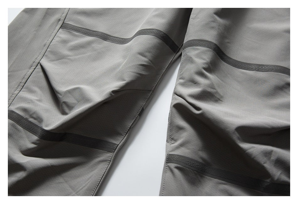 Close-up of gray pant legs showing dark horizontal trim and panel stitching.
