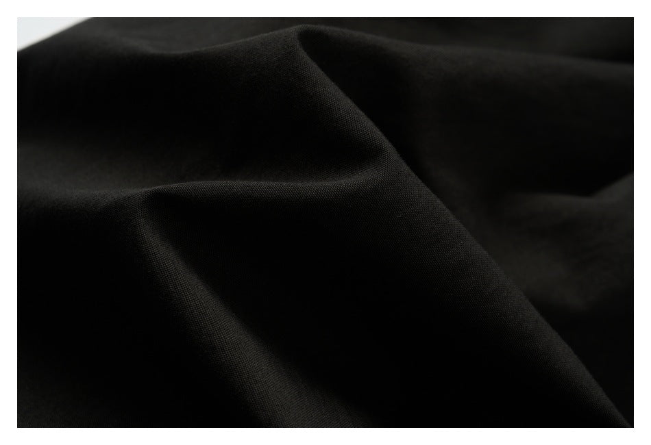 Close-up of black fabric draped into soft folds, showing its surface texture.