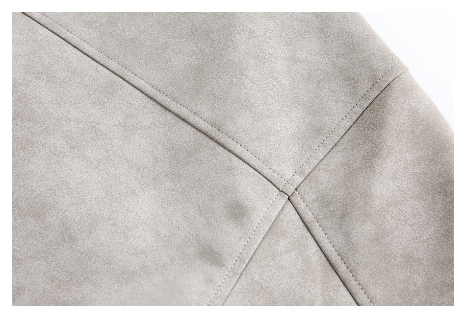 Close-up of a light taupe jacket showing intersecting stitched panels on a subtly mottled surface.