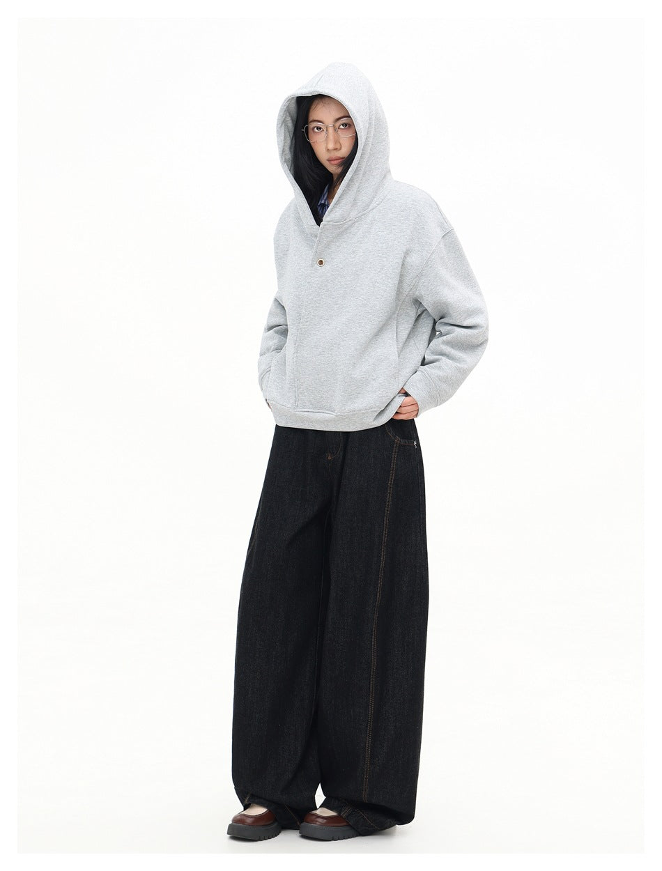 Model wearing the light gray oversized sweatshirt with its hood up and a single button at the front.