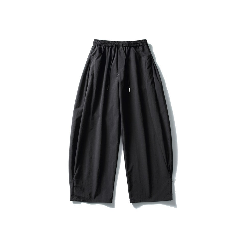 Black wide-leg drawstring pants, front flat lay, with rounded barrel-shaped legs and side pockets