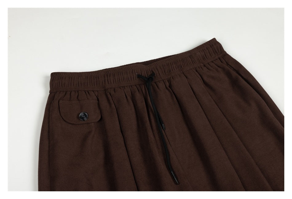 Close-up of dark brown pants showing the elastic drawstring waist and a buttoned pocket flap.