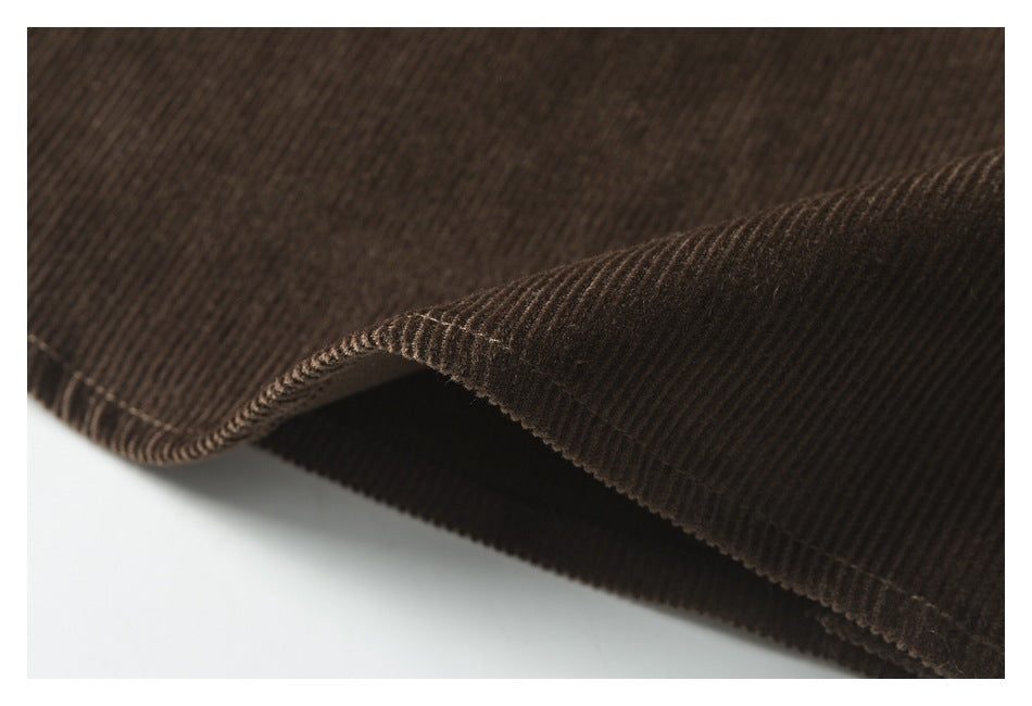Close-up of a curved edge on brown corduroy, showing the ribbed texture and stitched hem.