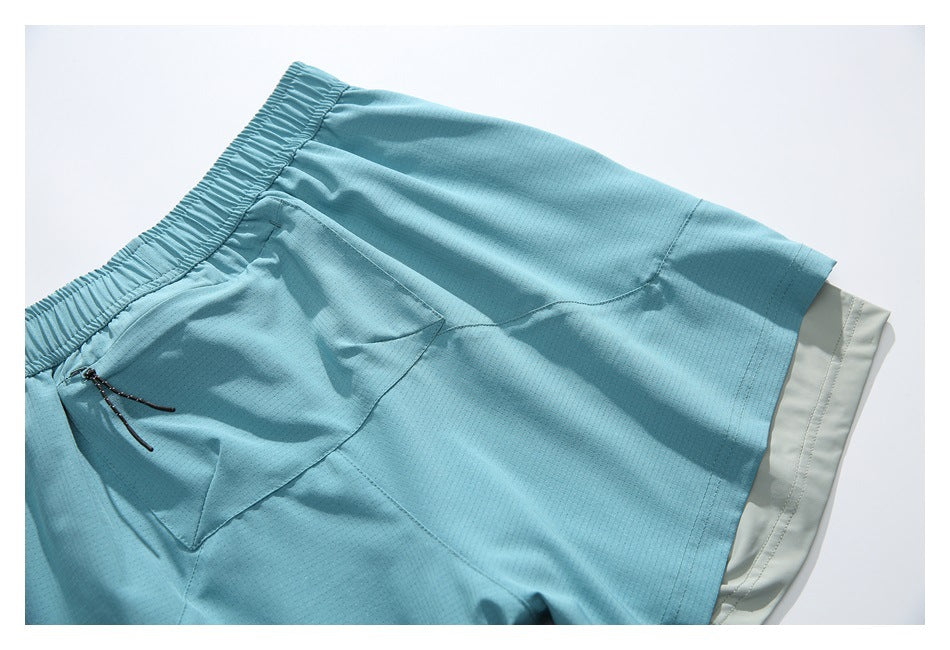 Aqua shorts laid flat, showing the elastic waistband, front pocket, and pale gray inner layer.
