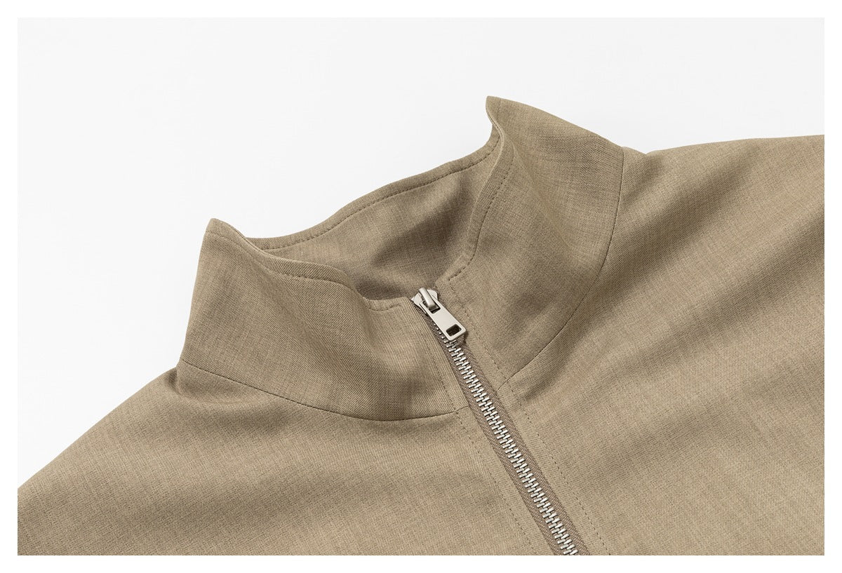 Close-up of the taupe jacket's stand collar and front metal zipper.