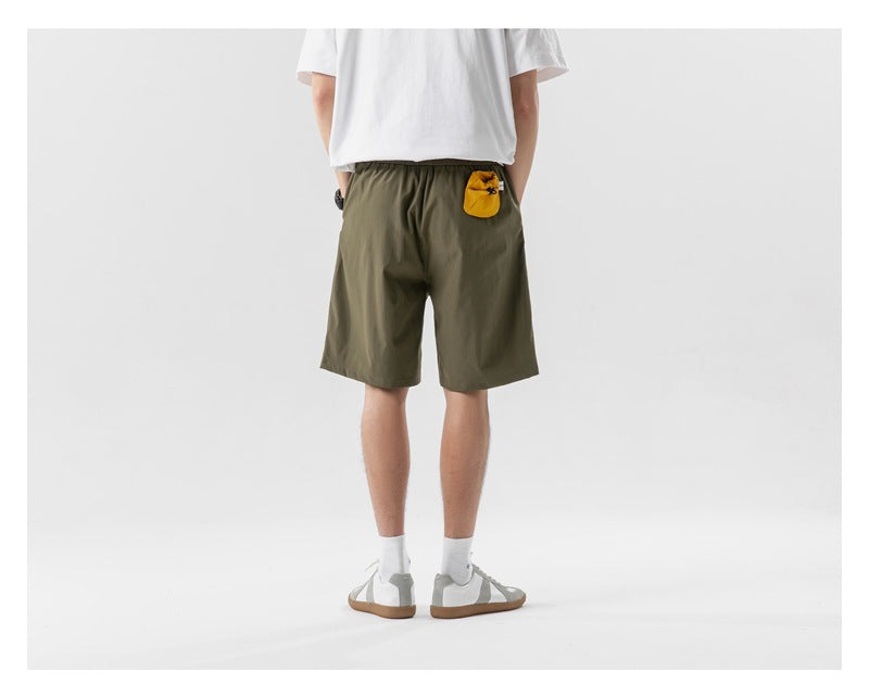 Back view of a model wearing olive shorts with a small yellow pouch at the waistband.