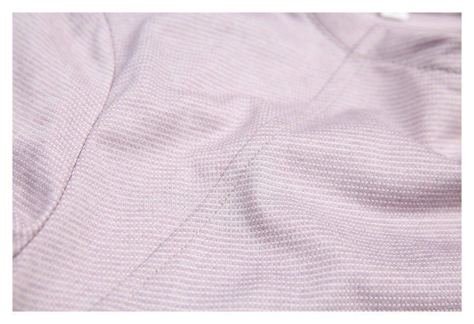 Extreme close-up of pale mauve patterned garment fabric, showing its fine texture and seam lines.