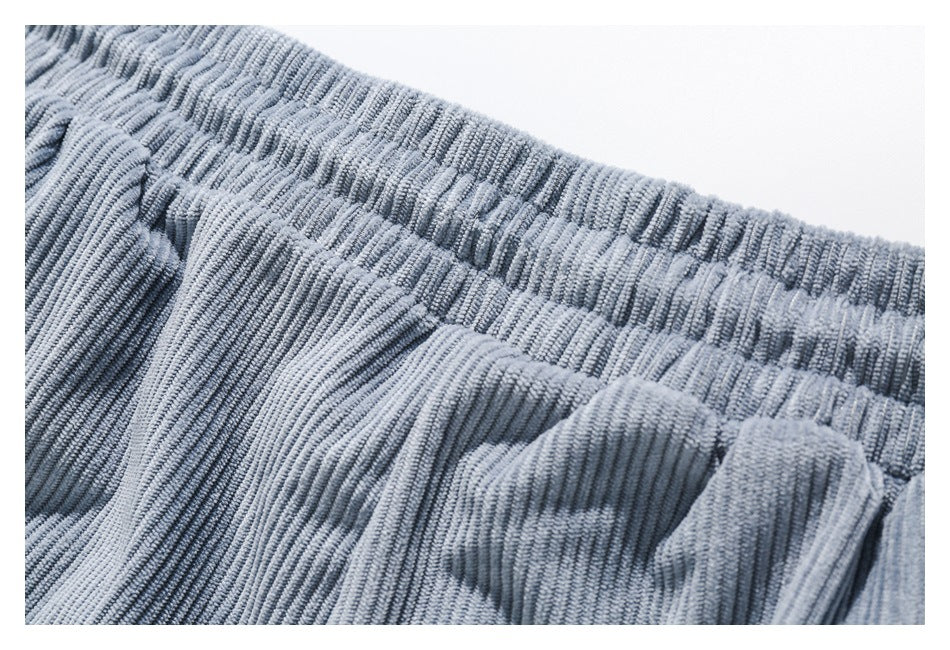 Close-up of gray ribbed corduroy fabric showing an elastic waistband and pocket seam.