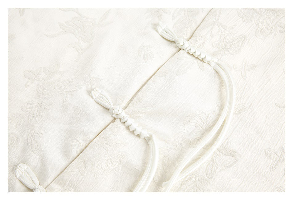 Close-up of ivory braided frog closures on floral-textured fabric.