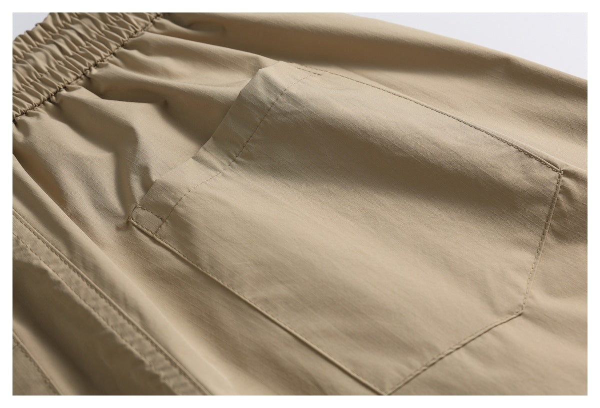 Close-up of tan trousers showing an elastic waistband and a large stitched pocket.