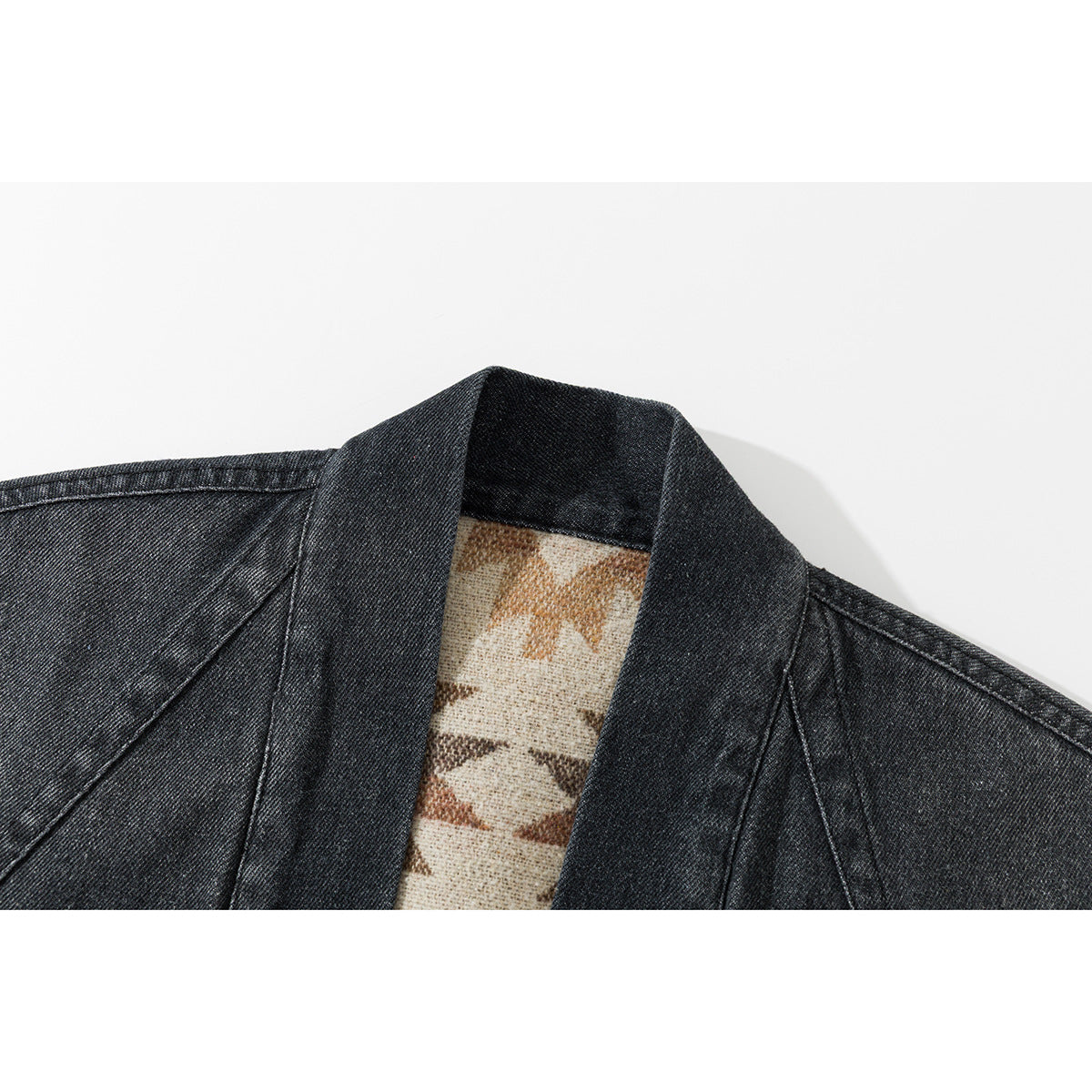 Close-up of a dark denim shawl collar with a glimpse of beige geometric-patterned lining.