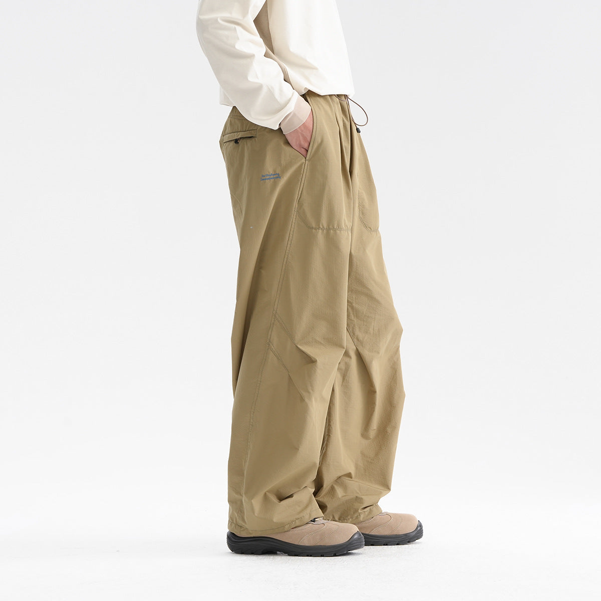 Model wearing loose khaki trousers with a drawstring waist, side pockets, and wide legs, shown from the side.