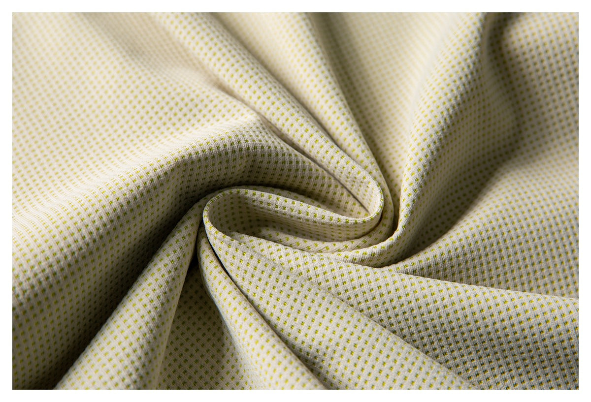 Close-up of draped off-white fabric patterned with small yellow-green dots.
