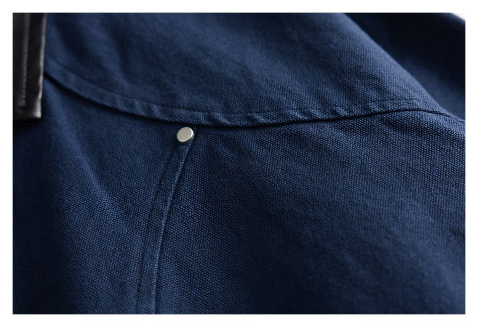 Close-up of a navy jacket's textured fabric, curved seam, and small metal snap.